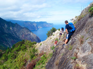 Levada do Caniçal. People climbing the rock. With cliffs in the distance.